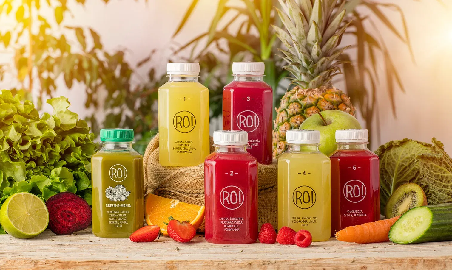 RO! cold-pressed juice bottles surrounded by fresh fruit and vegetables